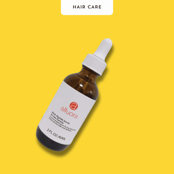 Alluora hair care serum bottle on yellow background.