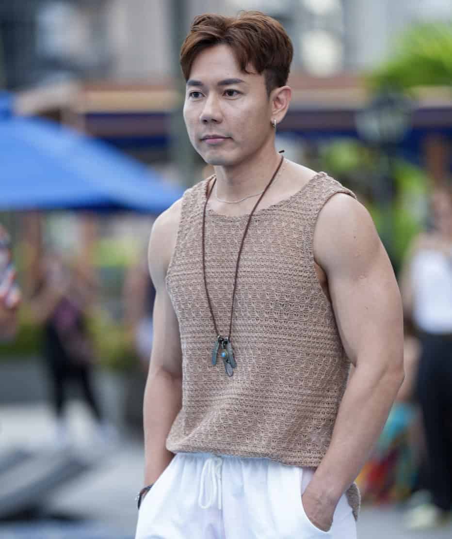 Men wearing sleeveless beige crochet top and white shorts outdoors.